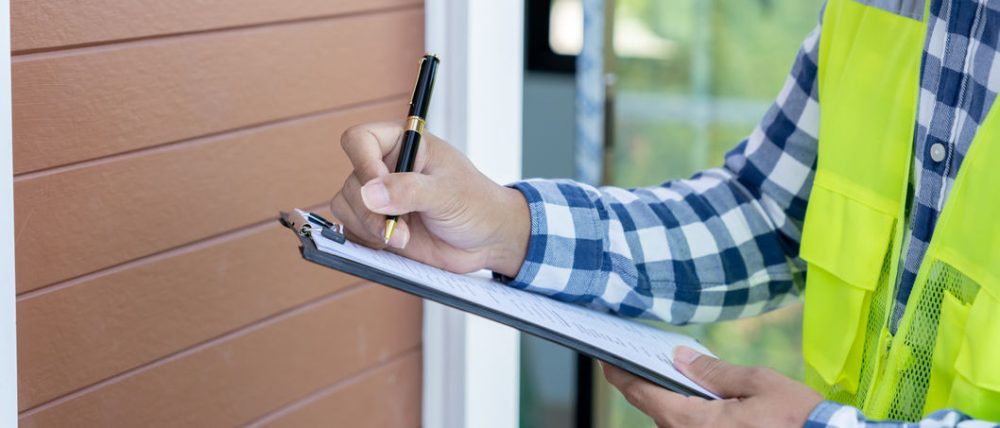 Home inspector filling out report while looking at exterior of a home