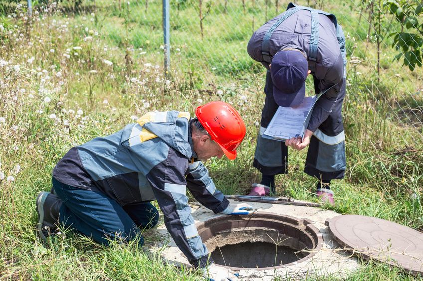 two workers inspecting a water well